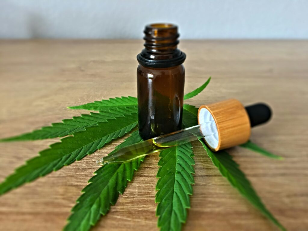 Bouteille d'huile de CBD posée sur des feuilles de cannabis